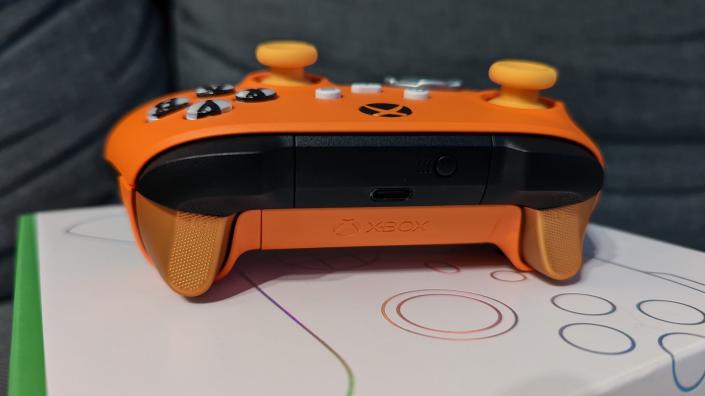 The top of an orange Xbox controller on its white packaging against a grey sofa. (Photo: Yahoo Gaming SEA)