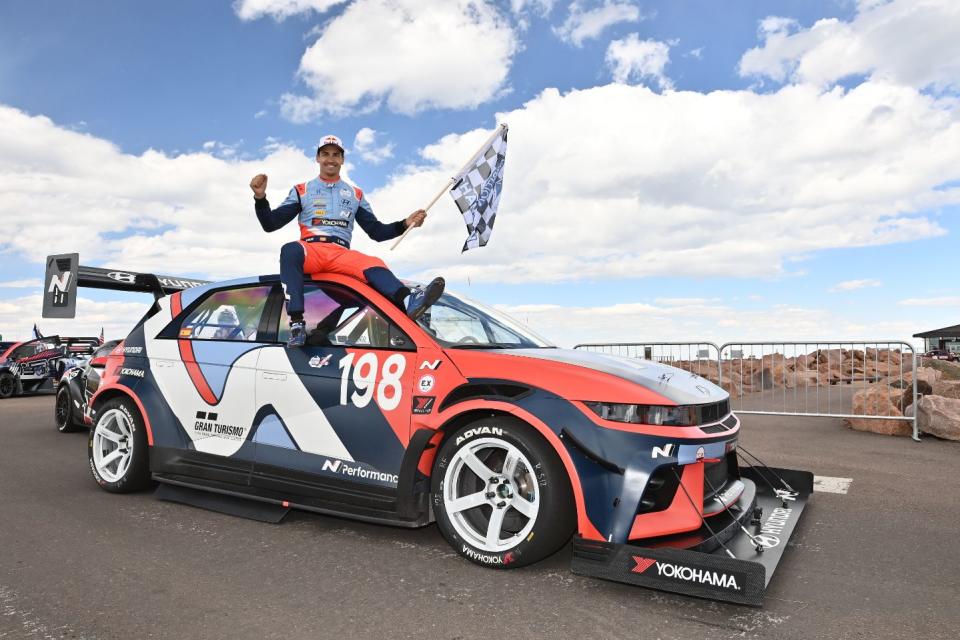 dani sorto holding checkered flag while sitting on hyundai ioniq 5 n ta at pikespeakinternationalhillclimb