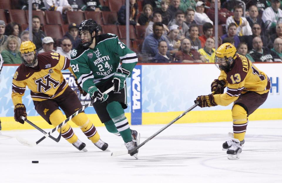 North Dakota's Jordan Schmaltz, center, brings the puck into the zone while flanked by Minnesota's Nate Condon, left, and Taylor Cammarata, right, during the first period of an NCAA men's college hockey Frozen Four tournament game on Thursday, April 10, 2014, in Philadelphia. (AP Photo/Chris Szagola)