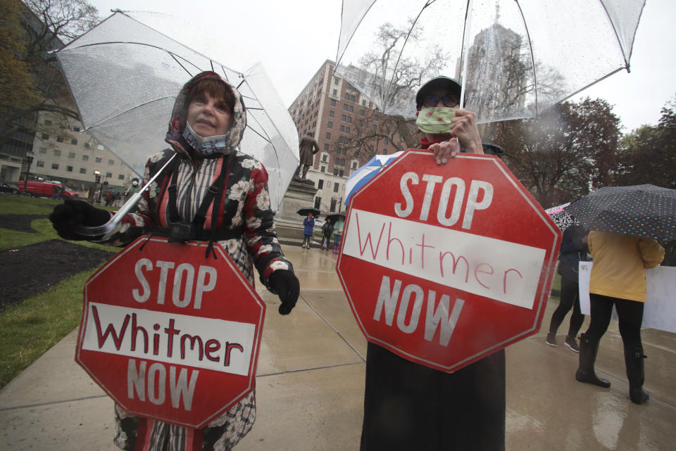 Protesters hold signs during a rally against Michigan’s coronavirus stay-at-home order at the State Capitol in Lansing, Mich., Thursday, May 14, 2020. (AP Photo/Paul Sancya)