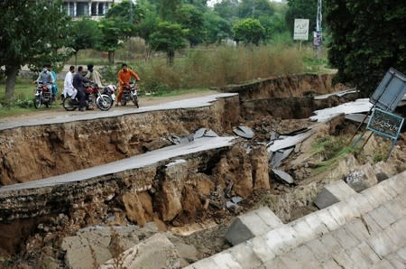 People on bikes gather near a damaged road after an earthquake in Mirpur
