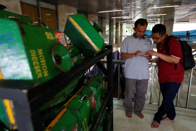 Men use their phones as alms boxes with QR codes are collected on a cart after Friday prayers at Istiqlal mosque in Jakarta