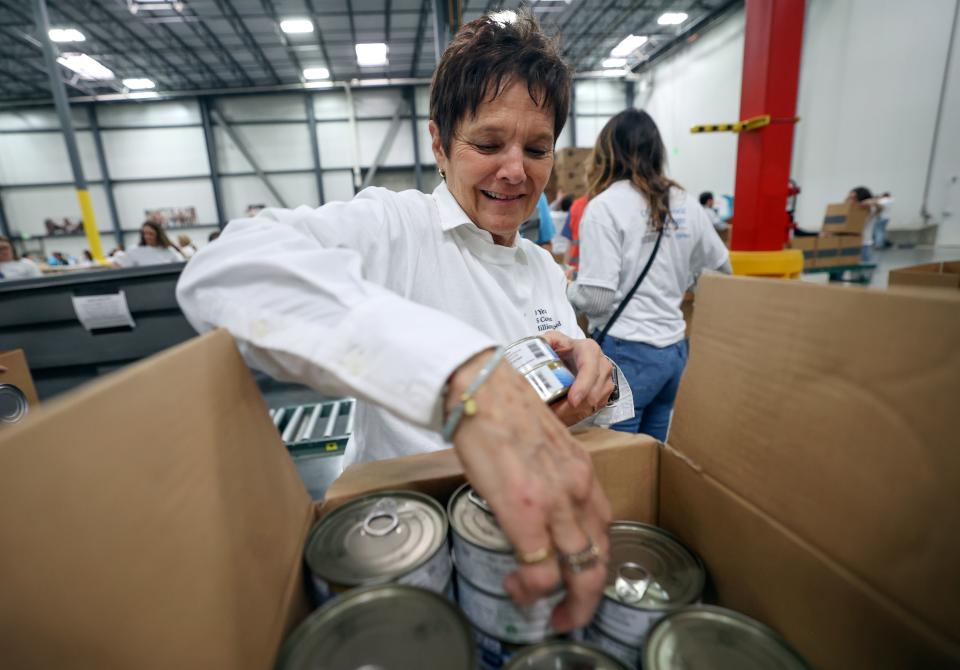 Molly Anderson grabs cans of tuna for food boxes during a service day, hosted by The Church of Jesus Christ of Latter-day Saints, to commemorate the 10th anniversary of its relationship with the United Nations World Food Programme and World Food Program USA, at Bishops’ Central Storehouse in Salt Lake City on Thursday, Feb. 8, 2024. | Kristin Murphy, Deseret News