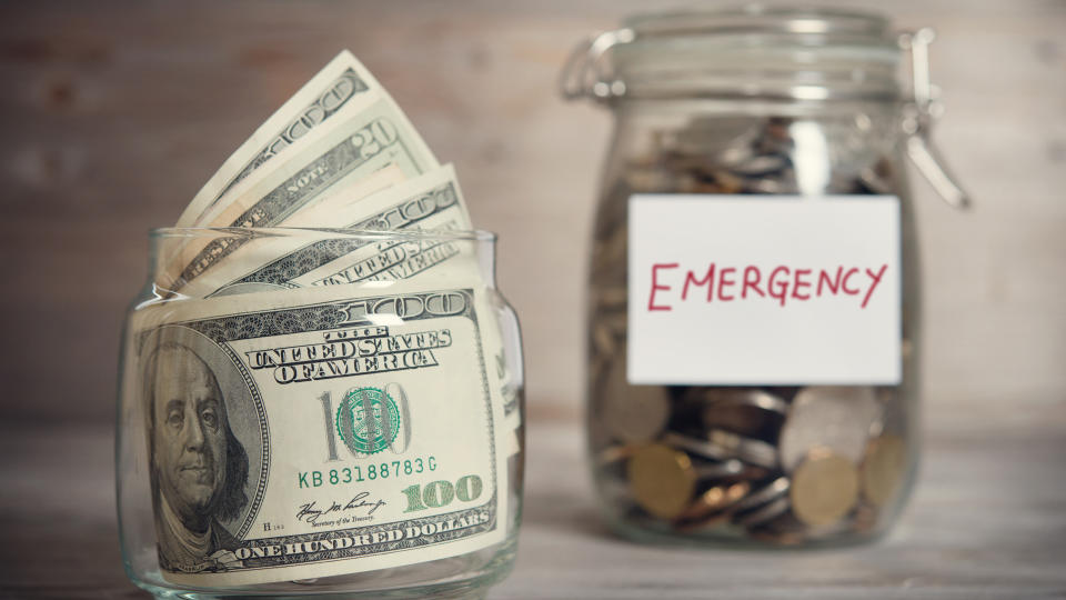 Dollars and coins in glass jar with emergency label, financial concept.