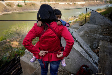 Cha Huilan, a 40-year old Lisu woman carries her daughter in her home in Lazimi village in Nujiang Lisu Autonomous Prefecture in Yunnan province March 24, 2018. Picture taken March 24, 2018. REUTERS/Aly Song