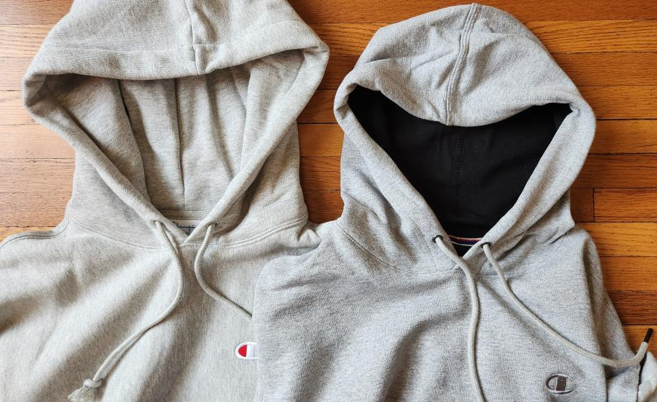 the hoods of two champion hoodies side by side on a wood floor 