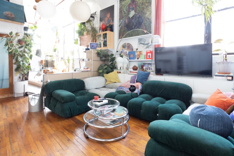 Multi colored sectional in plant filled eclectic apartment.