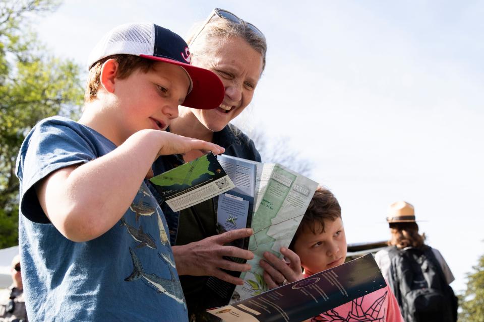 Roger Ettinger, 11, his mom Ailene Ettinger and Charlie Ettinger, 8, look at maps and information about the total solar eclipse on Arlington Lawn at Hot Springs National Park in Hot Springs, Arkansas on Monday, April 8, 2024. The family traveled from Seattle to view the eclipse and picked Hot Springs after seeing the weather would be good. Bob Ettinger said his parents are in Syracuse and Ailene’s parents are in Maine and they all will see the shadow of the moon within minutes of each other “It’s like you get a sense where you are in the solar system,” Bob Ettinger said.