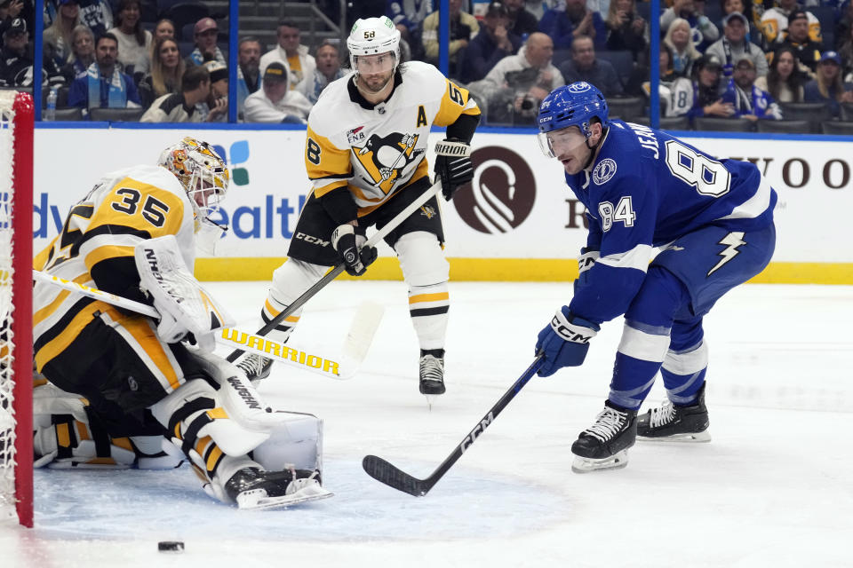 Tampa Bay Lightning left wing Tanner Jeannot (84) shoots wide of Pittsburgh Penguins goaltender Tristan Jarry (35) during the second period of an NHL hockey game Wednesday, Dec. 6, 2023, in Tampa, Fla. looking on is Pittsburgh's Kris Letang (58). (AP Photo/Chris O'Meara)