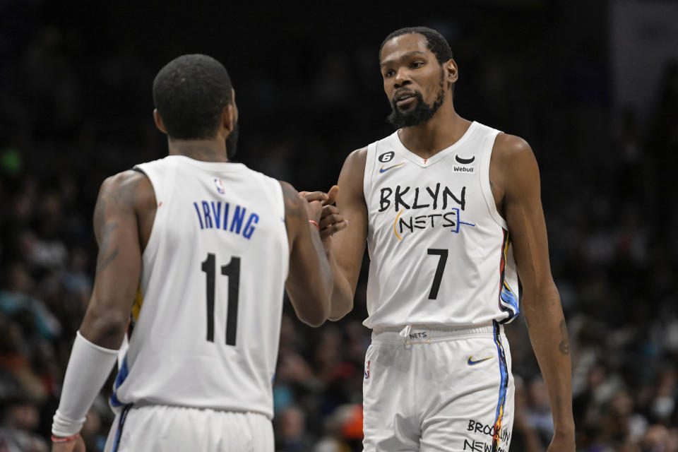 Brooklyn Nets guard Kyrie Irving (11) and forward Kevin Durant (7) shake hands during the second half of an NBA basketball game against the Charlotte Hornets, Saturday, Dec. 31, 2022, in Charlotte, N.C. (AP Photo/Matt Kelley)