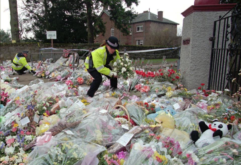 FILE - A police officer arranges bouquets of flowers in rows at a side entrance to Dunblane Primary School in Dunblane, Scotland Friday, March 15, 1996. A 1996 school shooting that killed 16 children in Dunblane was Britain's deadliest school shooting — and also the only one. (AP Photo/Lynne Sladky, File)