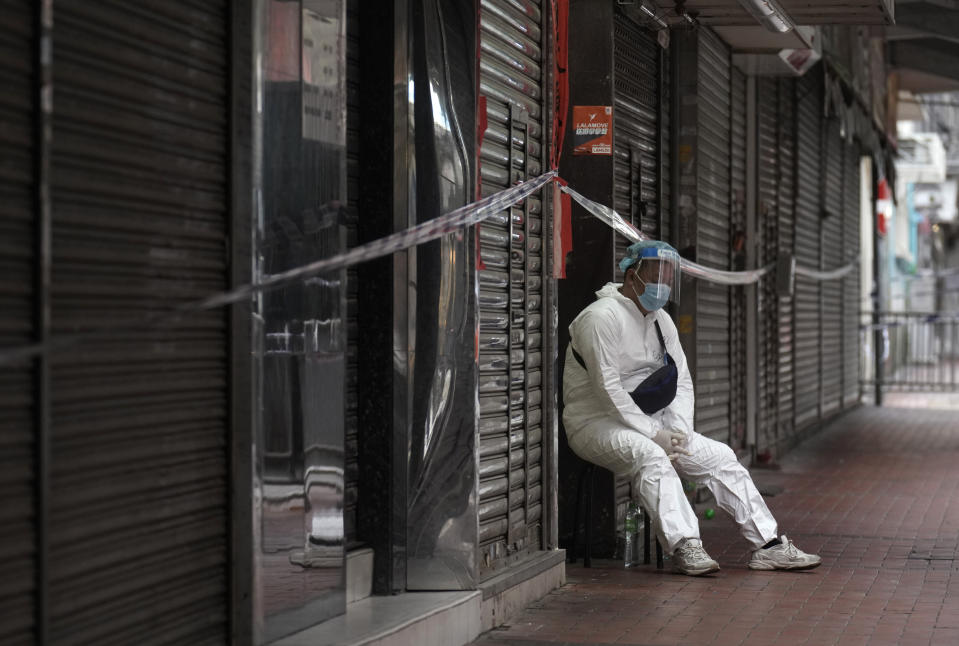 A government worker wearing personal protective equipment guards at the closed area in Jordan district, in Hong Kong, Sunday, Jan. 24, 2021. Thousands of Hong Kong residents were locked down Saturday in an unprecedented move to contain a worsening outbreak in the city, authorities said. (AP Photo/Vincent Yu)