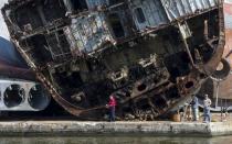 Men fish in front of wrecked ships at the Russian fleet base in Baltiysk in Kaliningrad region, Russia, July 19, 2015. REUTERS/Maxim Shemetov