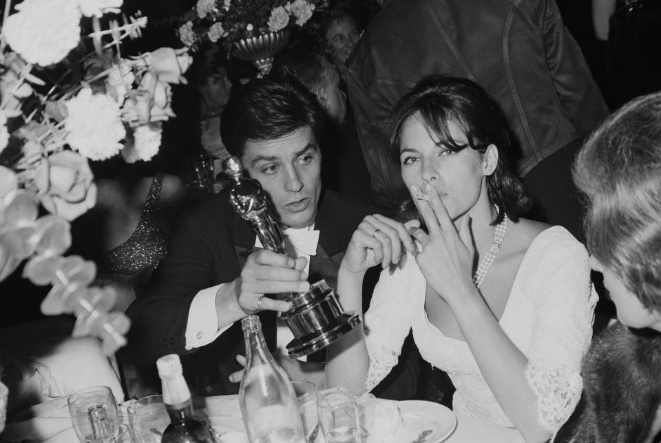 <p>French actor Alain Delon and his wife, French actress and fashion model Nathalie Delon (1941-2021) attend the 37th Academy Awards, held at the Santa Monica Civic Auditorium in Santa Monica, California, 5th April 1965. Alain Delon presented the Best Special Visual Effects award at the ceremony. (Photo by Graphic House/Archive Photos/Getty Images)</p>
