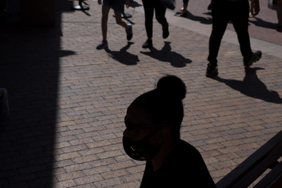 A shopper wearing a face mask sits in the shade at the Citadel Outlets in Commerce, Calif., Thursday, July 2, 2020. California Gov. Gavin Newsom on Thursday urged Californians to turn to their "better angels" and use common sense over the holiday weekend by wearing a mask and skipping traditional gatherings with family and friends. (AP Photo/Jae C. Hong)