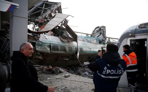 Police officers inspect the scene at the station after high-speed train crashed in Turkish capital Ankara  - Credit: Getty