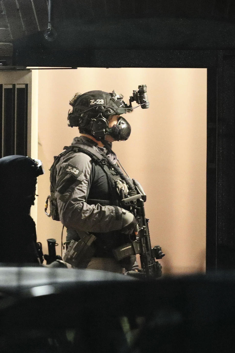 Armed police officers stand in a door at a block of flats off Basingstoke Road in Reading after an incident at Forbury Gardens park in the town centre of Reading, England, Saturday, June 20, 2020. Several people were injured in a stabbing attack in the park on Saturday, and British media said police were treating it as “terrorism-related.” (Steve Parsons/PA via AP)