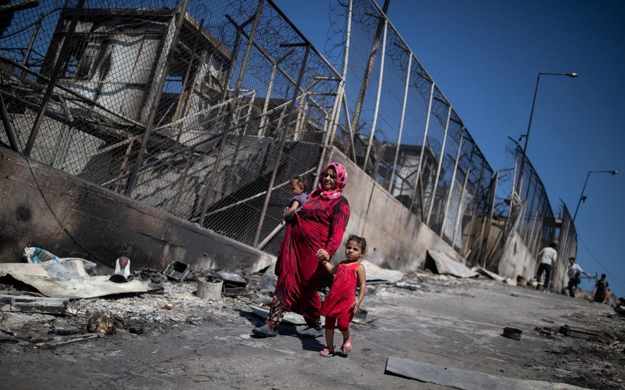 A woman and child in the burnt out ruins of Moria refugee camp on Lesbos  - Reuters