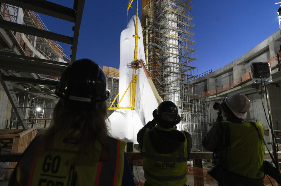 People take photos of Space Shuttle Endeavour at the site of the future Samuel Oschin Air and Space Center on Tuesday, Jan. 30, 2024, in Los Angeles. NASA's retired Space Shuttle Endeavour was carefully hoisted late Monday to be mated to a huge external fuel tank and its two solid rocket boosters at a Los Angeles museum where it will be uniquely displayed as if it is about to blast off. (AP Photo/Richard Vogel)