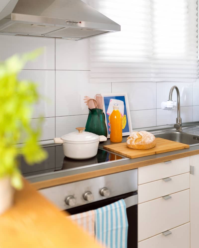 Kitchen with stainless steel appliances colorful vases and bread on a cutting board.