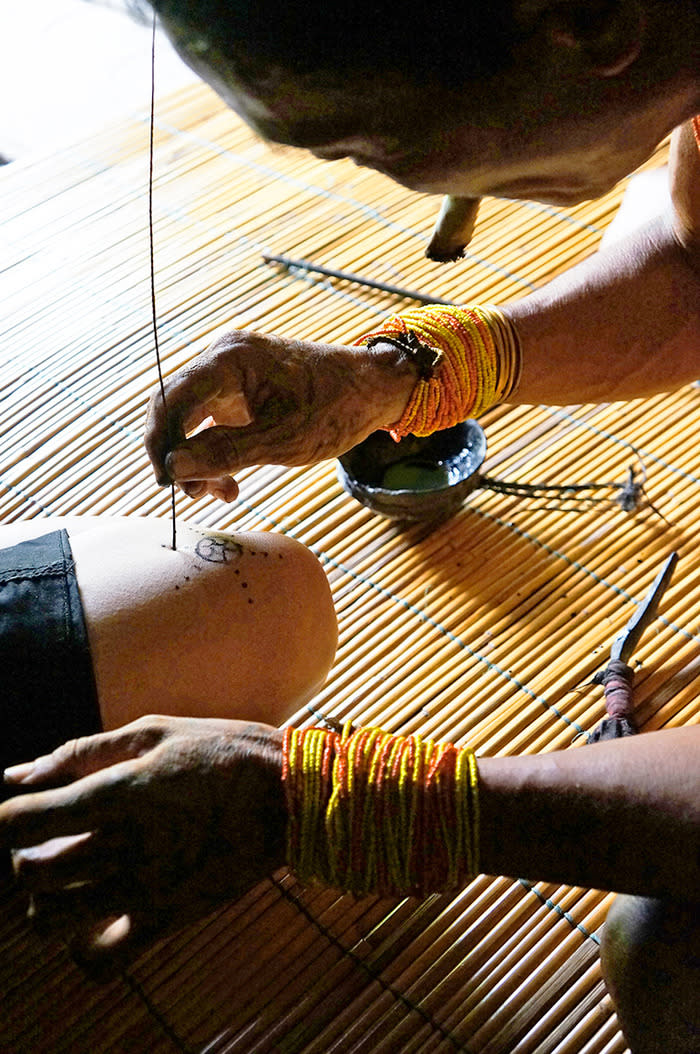 Tattoo in Mentawai: A sipatiti (Mentawai’s tattoo artist) draws a simple tattoo design using a sharp palm leaf's splintered ribs and natural ink made of sugar cane syrup and charcoal from burnt coconut shells. (