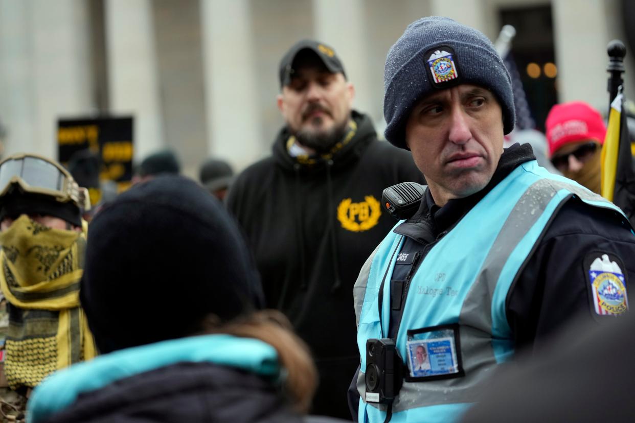 Officer Joshua Rhoads, a member of the Columbus police dialogue team, keeps distance between a group of far-right Proud Boys extremist group members and groups of counter-protesters who had gathered outside the Ohio Statehouse on the anniversary of the January 6 insurrection.