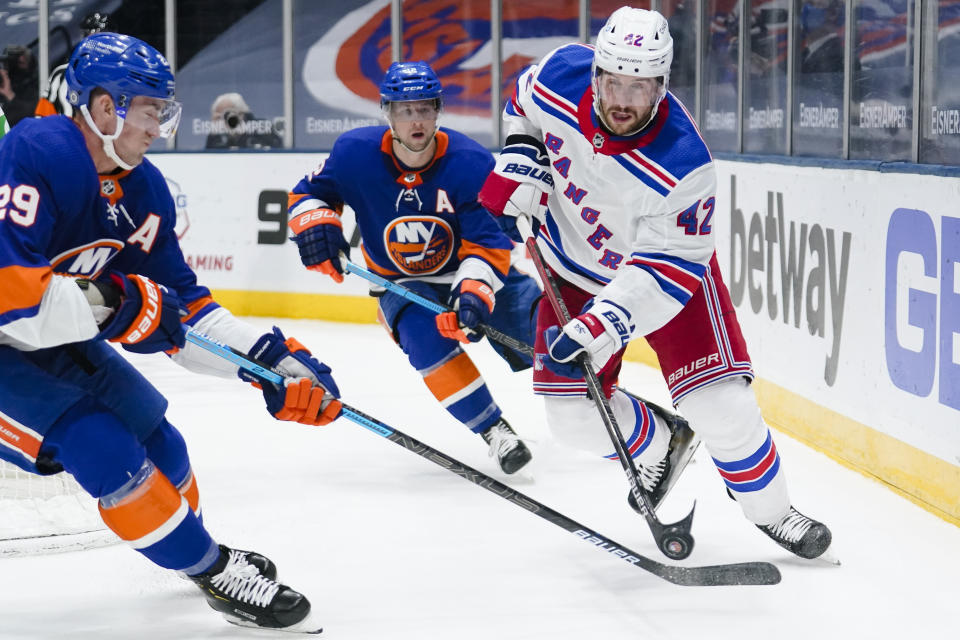 New York Rangers' Brendan Smith, right, passes away from New York Islanders' Brock Nelson, left, and Josh Bailey, center, during the second period of an NHL hockey game Sunday, April 11, 2021, in Uniondale, N.Y. (AP Photo/Frank Franklin II)