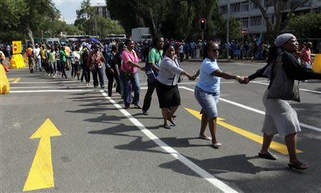 People hold hands in solidarity as they queue to view the body of former South African President Nelson Mandela outside the Union Buildings in Pretoria, December 11, 2013. REUTERS/Thomas Mukoya