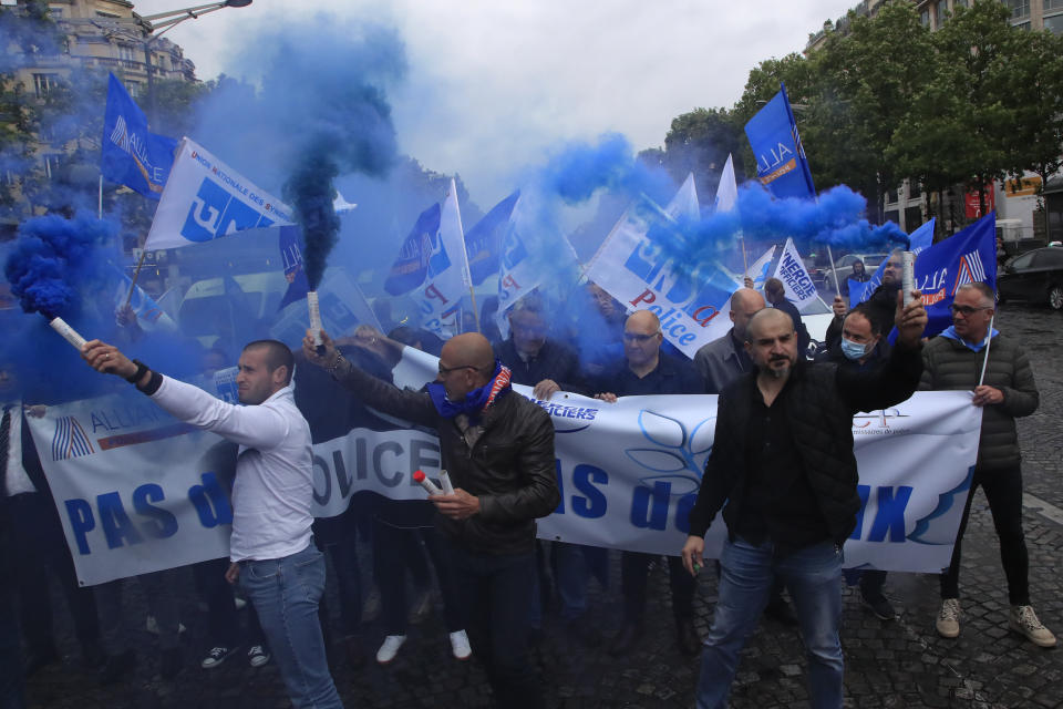 French police unionists fire blue flares as they demonstrate with a banner reading" No police, no peace" down the Champs-Elysee avenue, Friday, June 12, 2020 in Paris. French police are protesting a new ban on chokeholds and limits to what they can do during arrests, part of government efforts to stem police brutality and racism in the wake of global protests over George Floyd's death in the U.S. (AP Photo/Michel Euler)