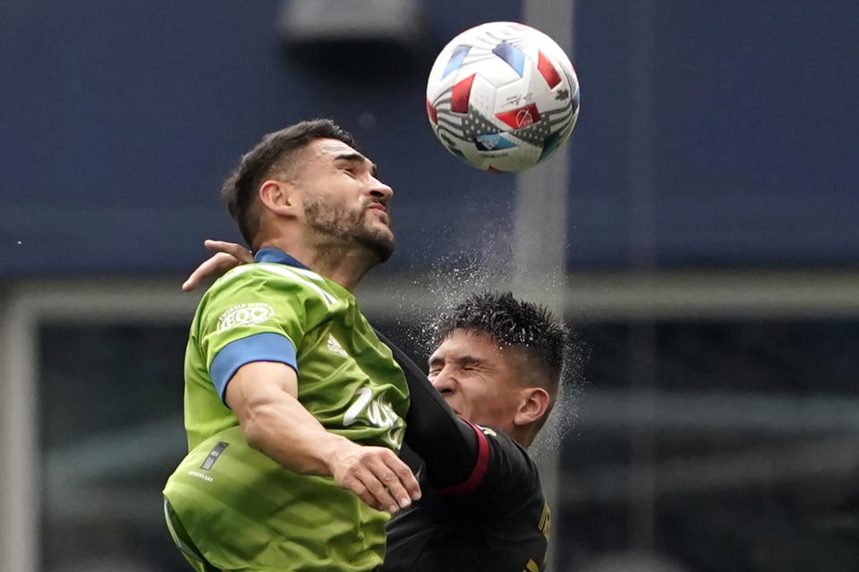 Seattle Sounders midfielder Cristian Roldan, left, heads the ball in front of Atlanta United midfielder Franco Ibarra, right, during the first half of an MLS soccer match, Sunday, May 23, 2021, in Seattle. (AP Photo/Ted S. Warren)