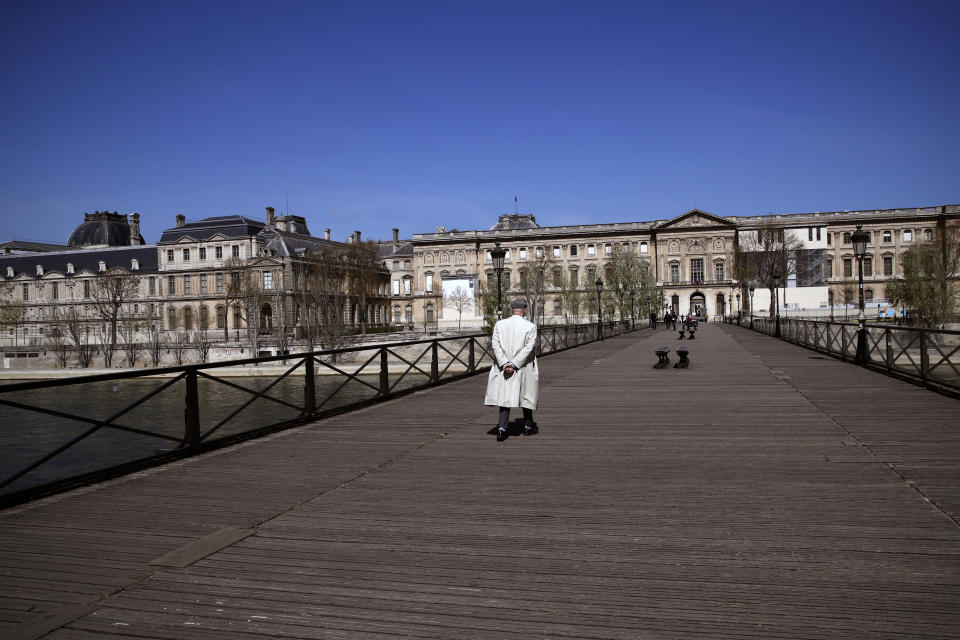 A man crosses a bridge during a nationwide confinement to counter the Covid-19, in Paris, Saturday, April 4, 2020. The new coronavirus causes mild or moderate symptoms for most people, but for some, especially older adults and people with existing health problems, it can cause more severe illness or death. (AP Photo/Christophe Ena)