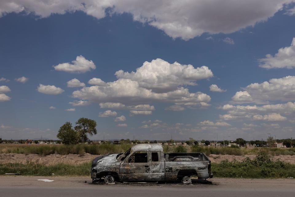 A pickup truck sits burned on the outskirts of Ciudad Juarez, Mexico, after cartel-related violence erupted at a local prison and spilled into the city's streets. September 2022