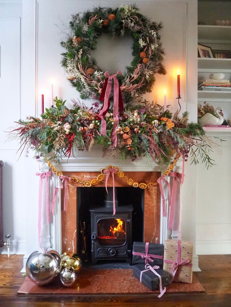 Fireplace mantel with decorative Christmas garlands made of dried fruit and winter foliage