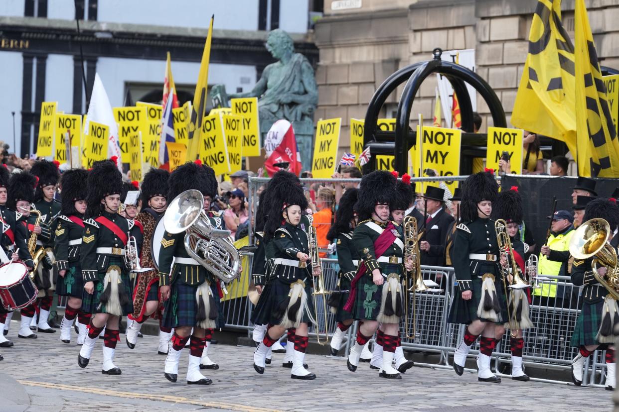 The Combined Cadet Force Pipes and Drums and the Cadet Military Band proceed down The Royal Mil past protesters (PA)