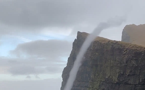 Video grab from the amazing footage of water flowing upwards on the  cliffs off Suðuroy in the Faroe Islands - a phenomenon known as a water spout. See SWNS story SWOCvortex. This is the incredible moment water flowed UPWARDS - after waves were caught in a rare sea vortex. Samy Jacobsen, 41, was out walking along the cliffs off Suðuroy in the Faroe Islands when he spotted a whirlwind of water rising from the waves. He watched as the vortex of spray climbed up the side of the 470m sea cliff - known as Beinisvørð - and billowing on to the cliff top, on Monday. Weather experts said it was a water spout - a spiralling pillar of air - which forms like a tornado over the water when a cliff edge spins the wind in a circle.  