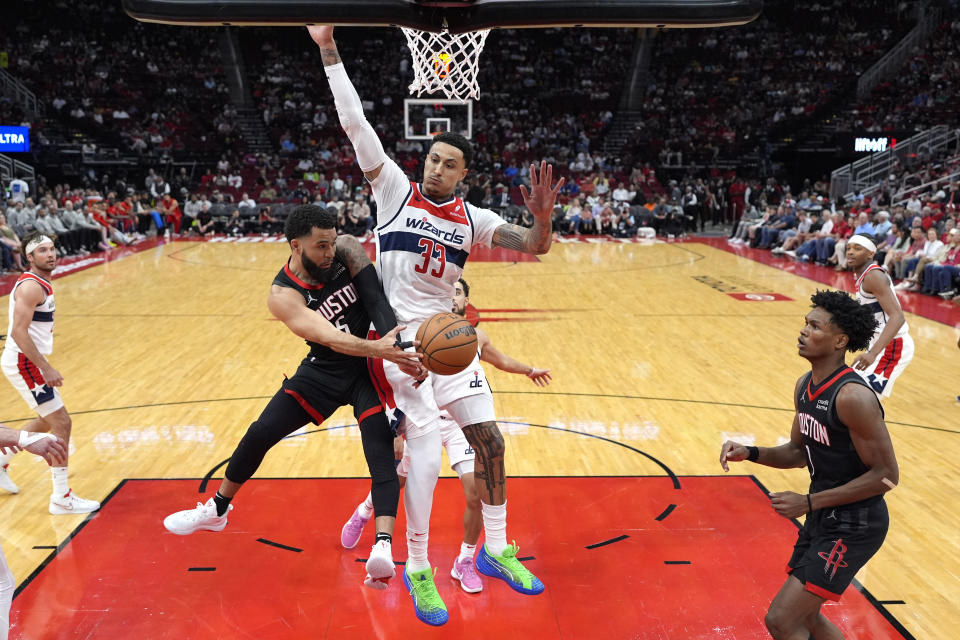 Houston Rockets' Fred VanVleet (5) passes the ball to Amen Thompson (1) as Washington Wizards' Kyle Kuzma (33) defends during the first half of an NBA basketball game Thursday, March 14, 2024, in Houston. (AP Photo/David J. Phillip)