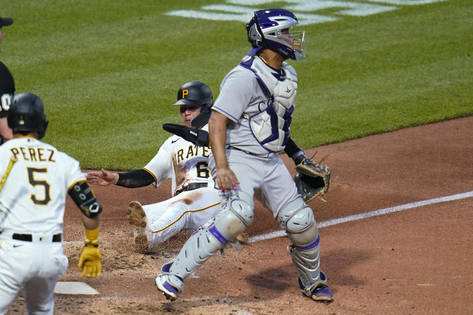 Pittsburgh Pirates' Diego Castillo scores next to Colorado Rockies catcher Elias Diaz, right, on a single by Cal Mitchell during the fifth inning of a baseball game in Pittsburgh, Tuesday, May 24, 2022. (AP Photo/Gene J. Puskar)