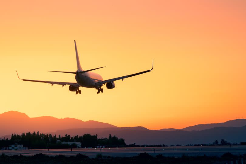 An airplane lands at sunset