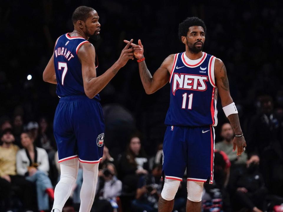 Kevin Durant and Kyrie Irving high-five during a Nets game in 2022.