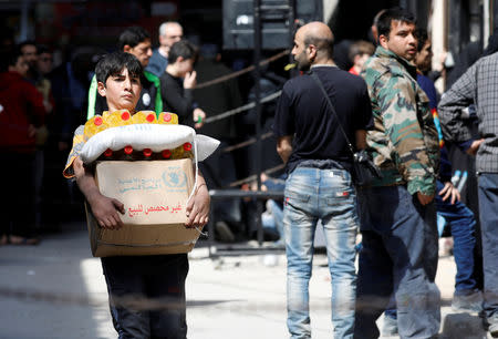 A boy holds a cardboard box of food aid received from World Food Programme in Aleppo's Kalasa district, Syria April 10, 2019. Picture taken April 10, 2019. REUTERS/Omar Sanadiki