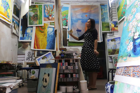 Ma Chunyan, 32, works on reproducing a masterpiece from an image of the original displayed on her mobile phone at her studio in Dafen Oil Painting Village in Shenzhen, Guangdong province, China December 5, 2018. REUTERS/Thomas Suen