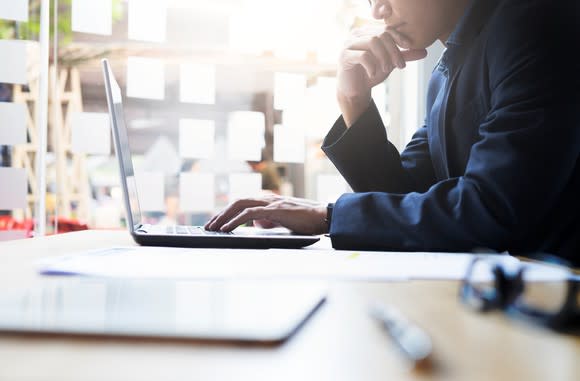 Man sitting at desk looking at computer.