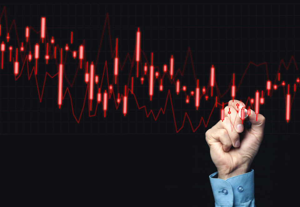 Hand grasping a marker and pointing to a red falling bar chart