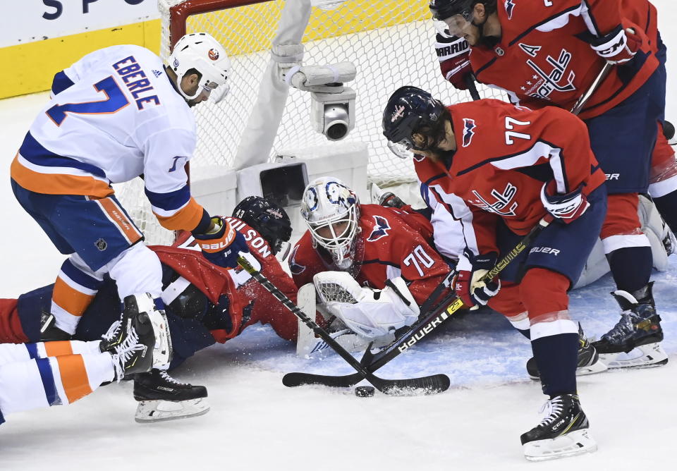 New York Islanders right wing Jordan Eberle (7) and Washington Capitals right wing T.J. Oshie (77) battle for the loose puck as Capitals goaltender Braden Holtby (70) looks on during the second period of an NHL Eastern Conference Stanley Cup hockey playoff game in Toronto, Wednesday, Aug. 12, 2020. (Nathan Denette/The Canadian Press via AP)