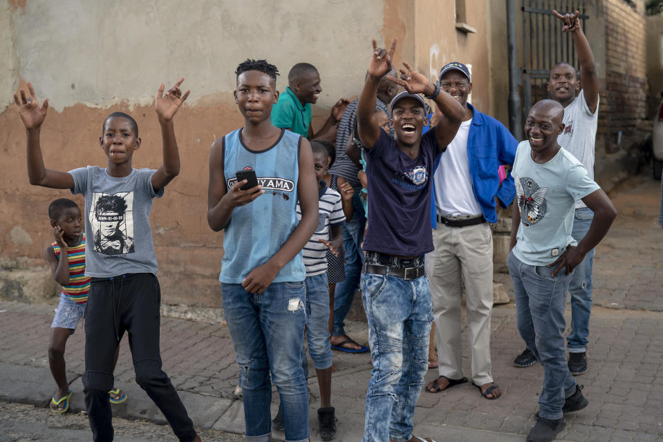 Young residents of the densely populated Alexandra township east of Johannesburg cheer at the photographer following a South African National Defense Forces patrol Friday, March 27, 2020. South Africa went into a nationwide lockdown for 21 days in an effort to mitigate the spread to the coronavirus, but in Alexandra, many people were gathering in the streets disregarding the lockdown. The new coronavirus causes mild or moderate symptoms for most people, but for some, especially older adults and people with existing health problems, it can cause more severe illness or death.(AP Photo/Jerome Delay)