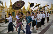 In this April 8, 2014 photo, Buddhist devotees carry their sons and nephews to circumambulate the Shwedagon pagoda in hopes of earning a blessing from Buddha ahead of their ordination as Buddhist monks, Yangon, Myanmar. With golden umbrellas covering them from equatorial sun, boys in princely attire are hoisted onto the shoulders of their fathers and uncles, part of a ritual carried out this time every year at Buddhist pagodas all over Myanmar: Young would-be-novices preparing to enter the monk hood. (AP Photo/Gemunu Amarasinghe)