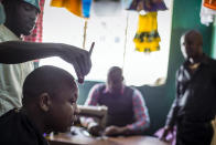 <p>A barber works with precision at a shop in Maramba, a township of Livingstone, Zambia. </p>