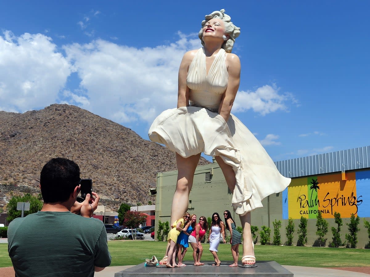 Women pose for a photo beneath the ‘Forever Marilyn’ statue in 2012 (AFP via Getty Images)