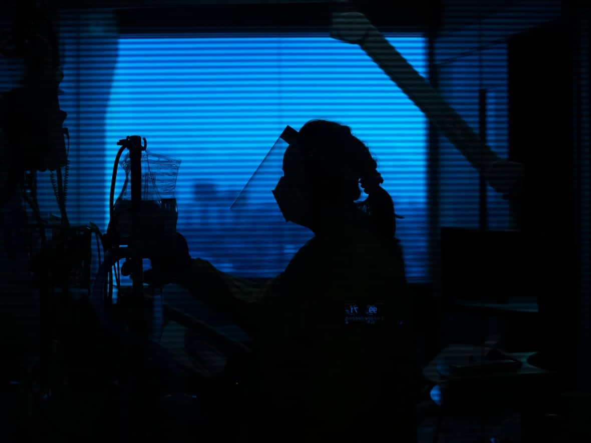 A registered nurse attends to a COVID-19 patient in the respirology unit at the Humber River Hospital in Toronto in January 2022. (Nathan Denette/Canadian Press - image credit)