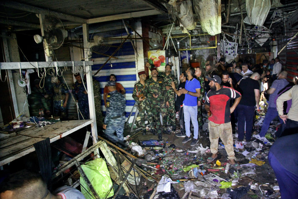 People and security forces gather at the site of a bombing in Wahailat market in Sadr City, Iraq, Monday, July 19, 2021. A roadside bomb attack targeted a Baghdad suburb Monday, killing at least 18 people and wounding dozens of others at a crowded market, Iraqi security officials said. (AP Photo/Khalid Mohammed)